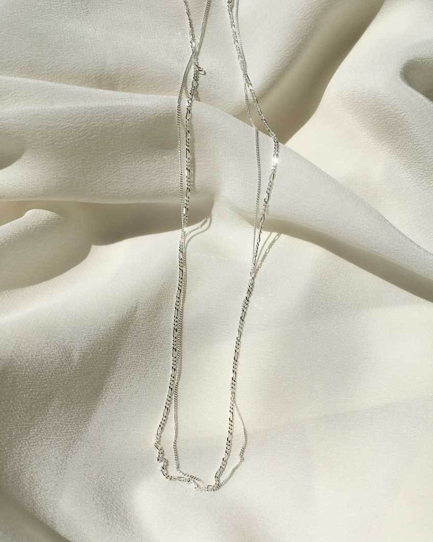 Figaro link chain (Sterling Silver) and Whisper Chain for layering by Sit &amp; Wonder, shown on an ivory silk background